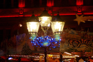 Eine Straßenlaterne mit dekorativen Lichtern und Schmuck in einer Stadt in der Nacht, mit einem Gebäude im Hintergrund.