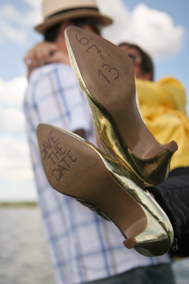 Frauen-High-Heels mit Text darauf, gehalten von einer Person mit sichtbaren Händen.