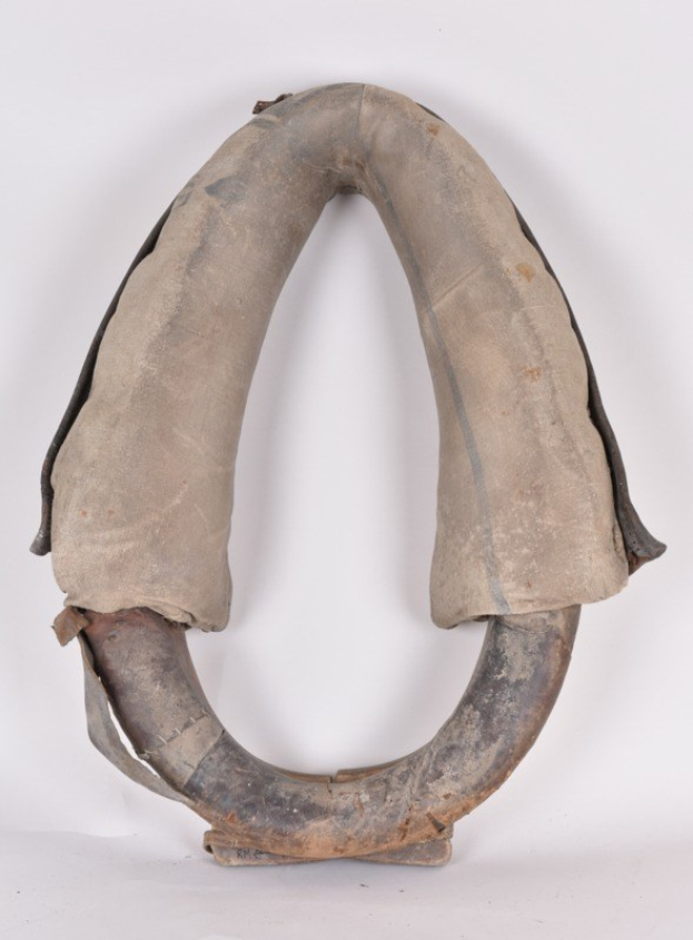 Nahaufnahme eines wetterfesten Metallrettungsring mit gebogener Form, Griff oben und sichtbaren Kratzern und Dellen auf einer weißen Oberfläche.