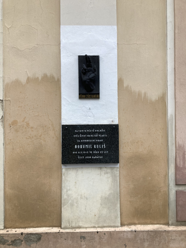 Schwarze Tafel an einem Gebäude mit einer Hand darauf, mit Inschrift, wahrscheinlich ein Holocaust-Mahnmal.