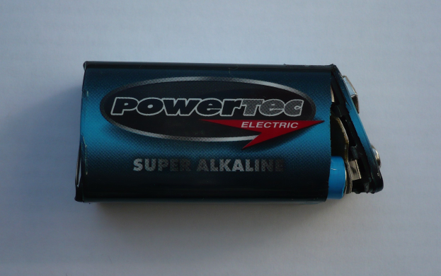 Blue Powertec Super Alkaline battery on a white surface, labeled "Powertec" in bold lettering.