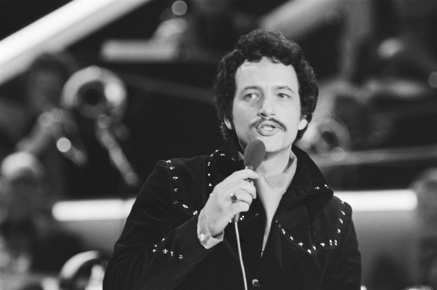 Schwarzes und weißes Foto von Elvis Presley, der ein Mikrofon hält und auf einer Live-Aufführung zu sehen ist.