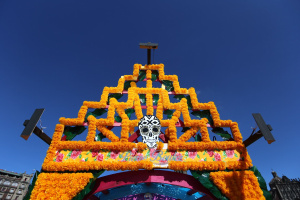 Ein Día de los Muertos-Bogen, geschmückt mit Blumen und einem Schädel, vor einem klaren blauen Himmel in Mexiko-Stadt.