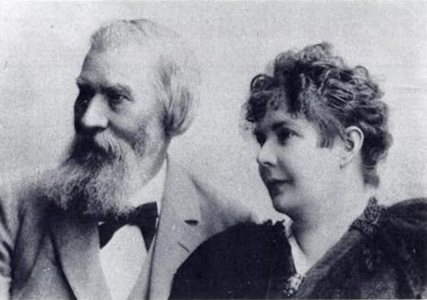 Ein Schwarz-Weiß-Foto von Gustav Klimt und seiner Frau, beide sitzend, mit Klimt im Anzug und seiner Frau, die ihn liebevoll anschaut.