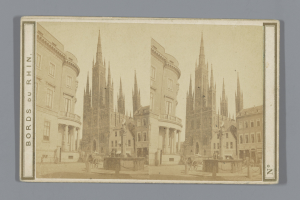 Ein altes Foto einer Stadtstraße mit Gebäuden, Straßenlaternen, Pferdefuhrwerken und Menschen, gesäumt von Bäumen.