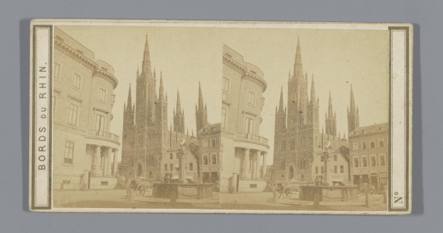 Ein altes Foto einer Stadtstraße mit Gebäuden, Straßenlaternen, Pferdefuhrwerken und Menschen, gesäumt von Bäumen.