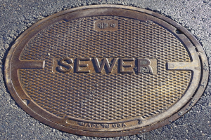 Metallschachdeckel auf der Straße mit der Aufschrift "Kanal"