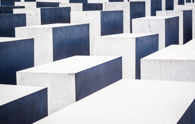 Luftaufnahme des Holocaust-Mahnmals für die ermordeten Juden Europas in Berlin, mit zahlreichen weißen und blauen Betonplatten in einem Gittermuster.