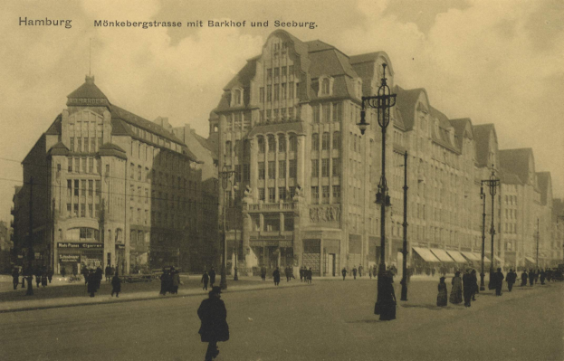 Altes Schwarz-Weiß-Foto von Fußgängern auf einer Straße in Hamburg, Deutschland, gesäumt von Gebäuden, Straßenlaternen, Autos und einem bewölkten Himmel mit Text oben.