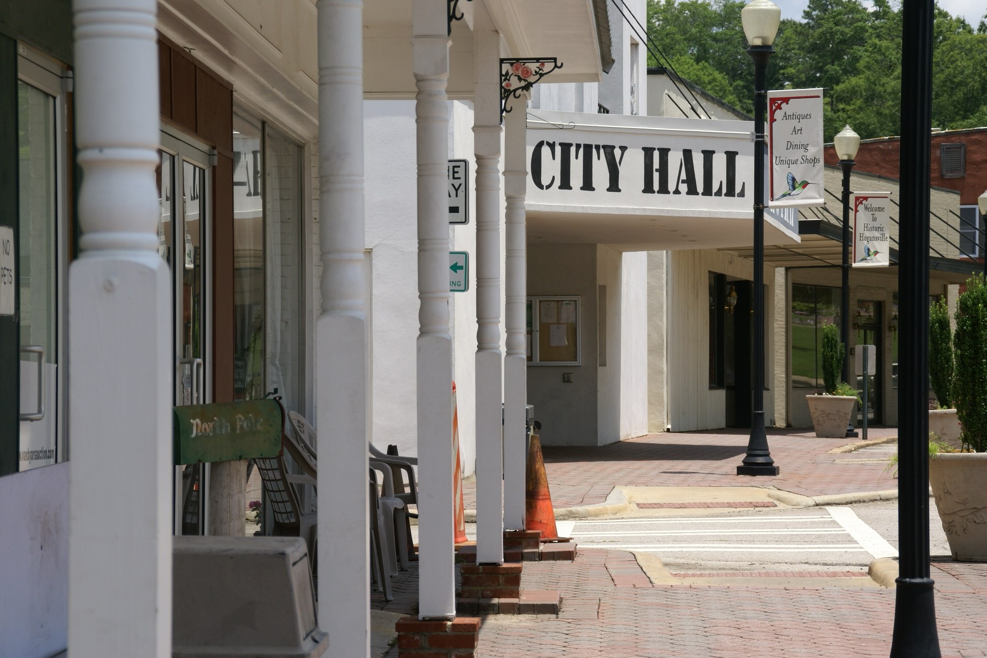 Rathaus mit umliegenden Gebäuden, Straßeninfrastruktur, Fahrzeugen und Grünanlagen unter einem bewölkten Himmel.