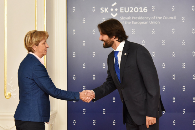 Bundeskanzlerin Angela Merkel und Bundeskanzler Joachim Gauck schütteln Hände vor einem Banner mit der Aufschrift "EU-Gipfel" mit einer Tür im Hintergrund.